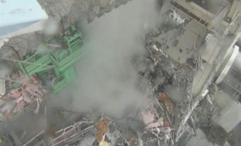 An overview shows smoke rising from the interior of reactor No. 4 at the Fukushima Daiichi nuclear power plant complex in this still image taken from a March 24, 2011 handout video released on April 1, 2011.